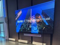 Image of a wall screen displaying an image with text that reads, "22/23 HT Partner Open House"