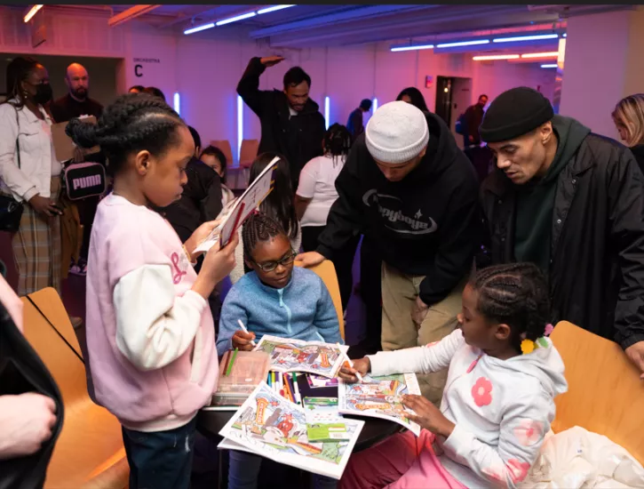 Kids and adults sitting and standing at a table coloring.