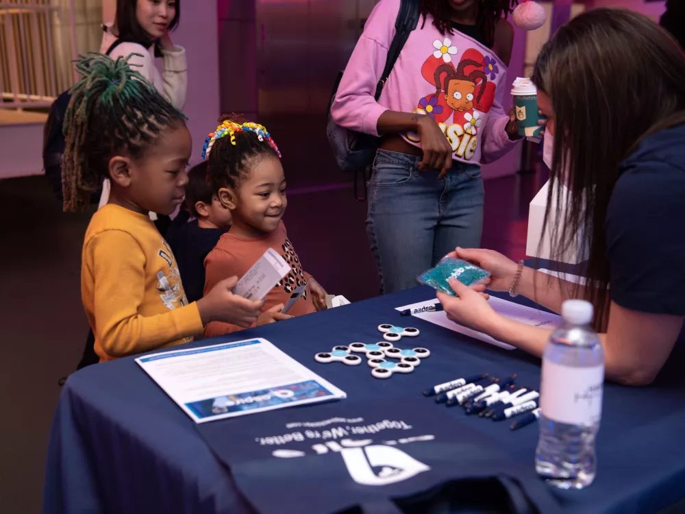 Two young girls at a info table for Aspire