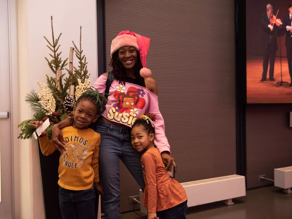 Mother and two young children smiling at the camera in the HT Lobby.