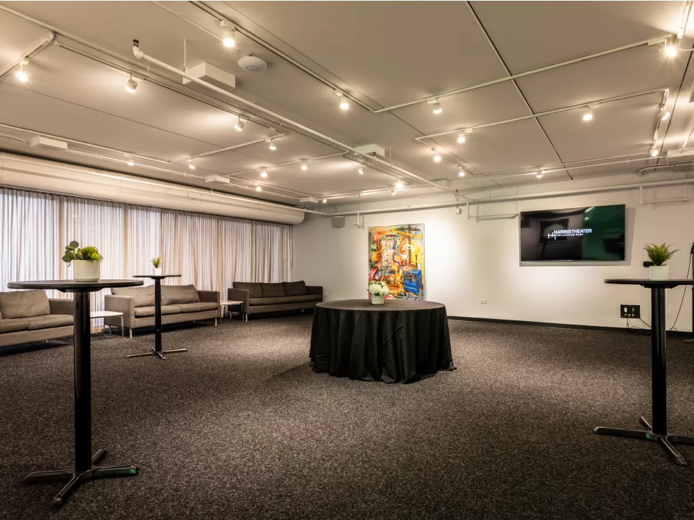 Room with couches, high tables, table with a linen, and a tv mounted on the wall