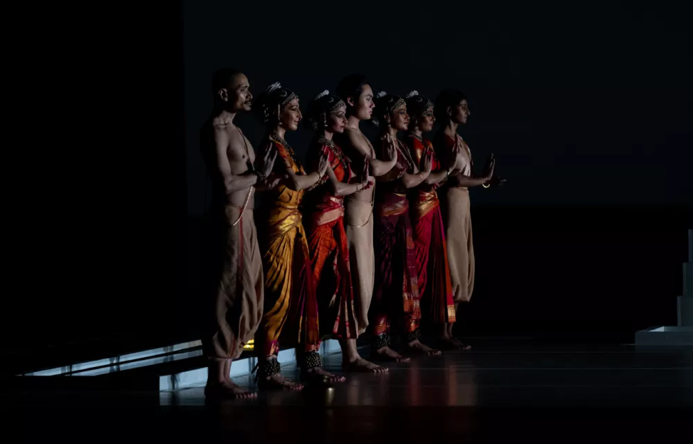 Several dancers stand in a line on stage ready to perform.