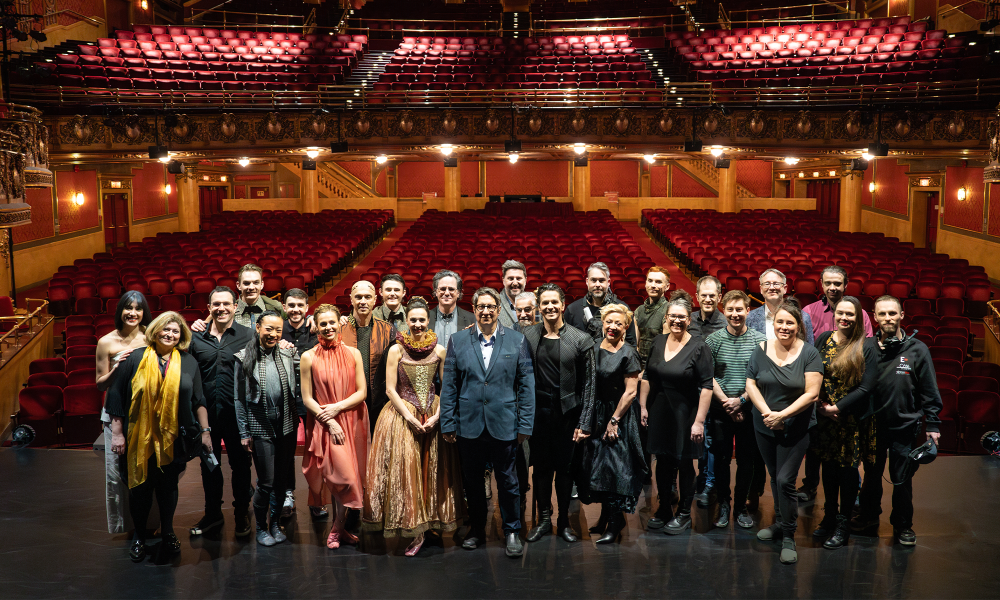 The ensemble and crew of Hamlet stand on stage in front of an empty theatre.