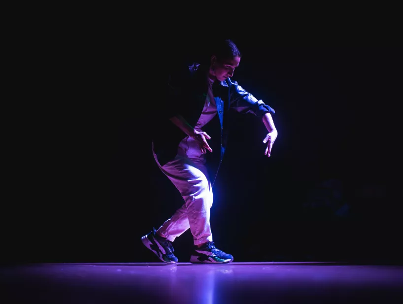 A spotlight hits Mai Le on stage while they perform.