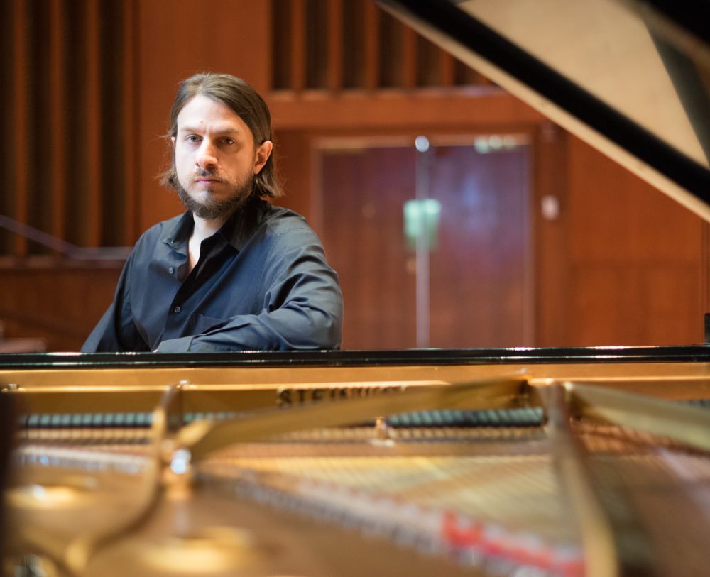 Thomas Schwan leans on a piano.