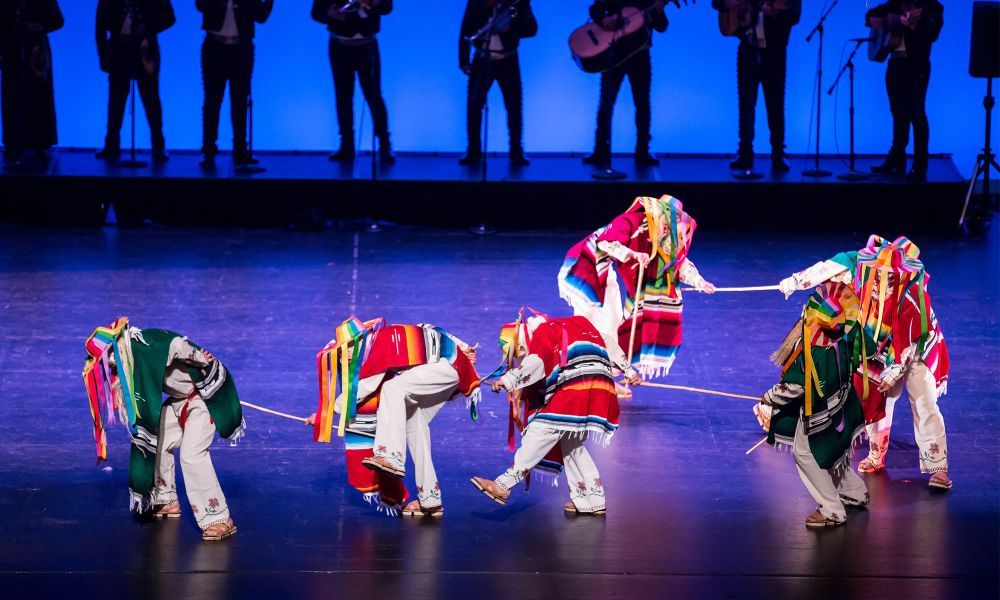 A group of dancers wearing serapes and traditional Mexican folklorico dance attire.