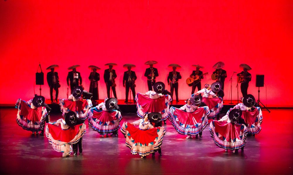 A Mexican folkloric dance group wearing traditional mariachi suites and dresses.