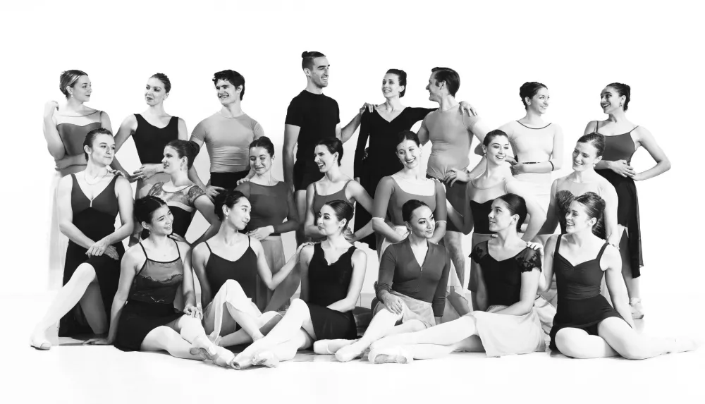 The Artists of Ballet 5:8 pose in 3 lines smiling and looking at one another.  