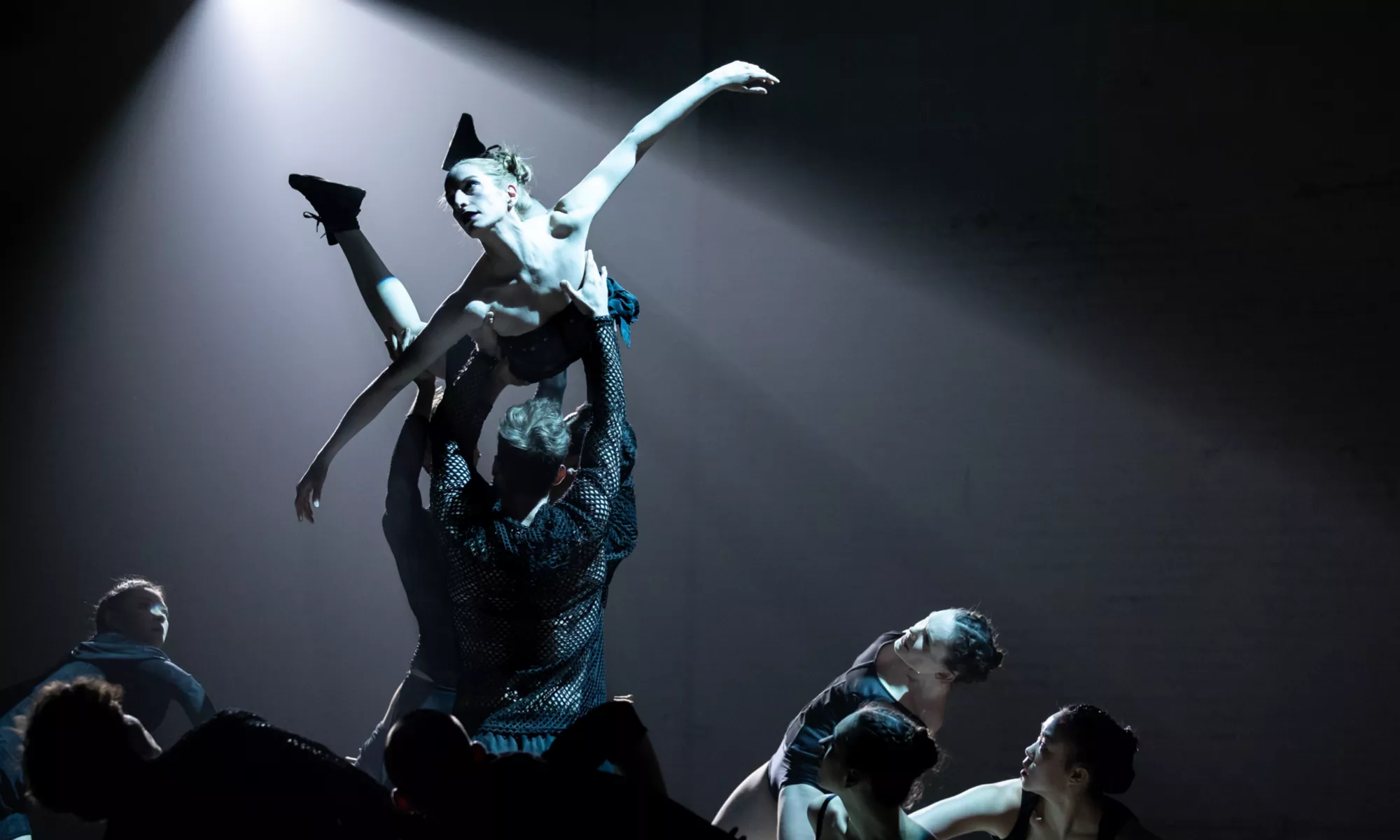 Spotlight of a dance holding another dancer in the air