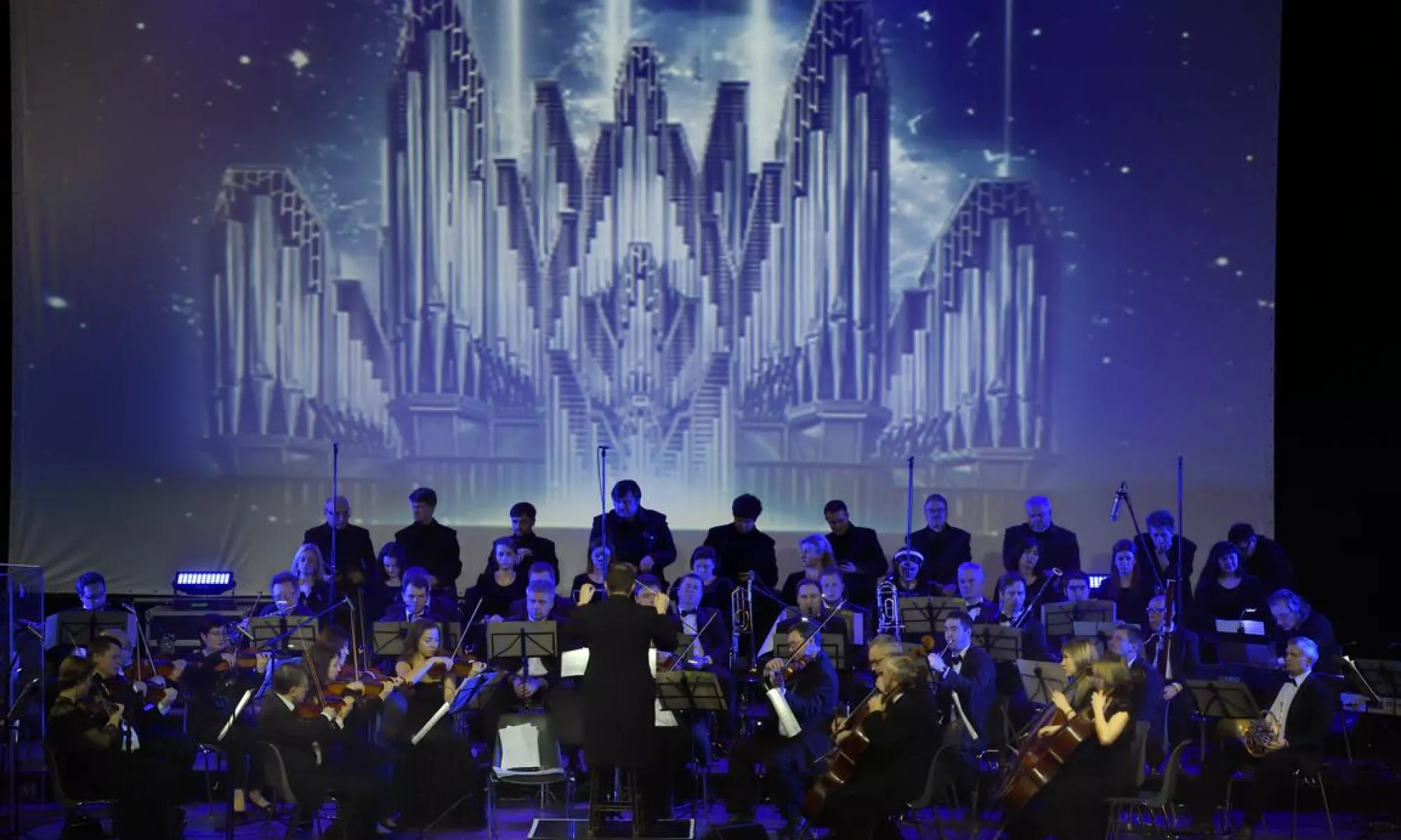 An orchestra on stage with projections happening behind them.