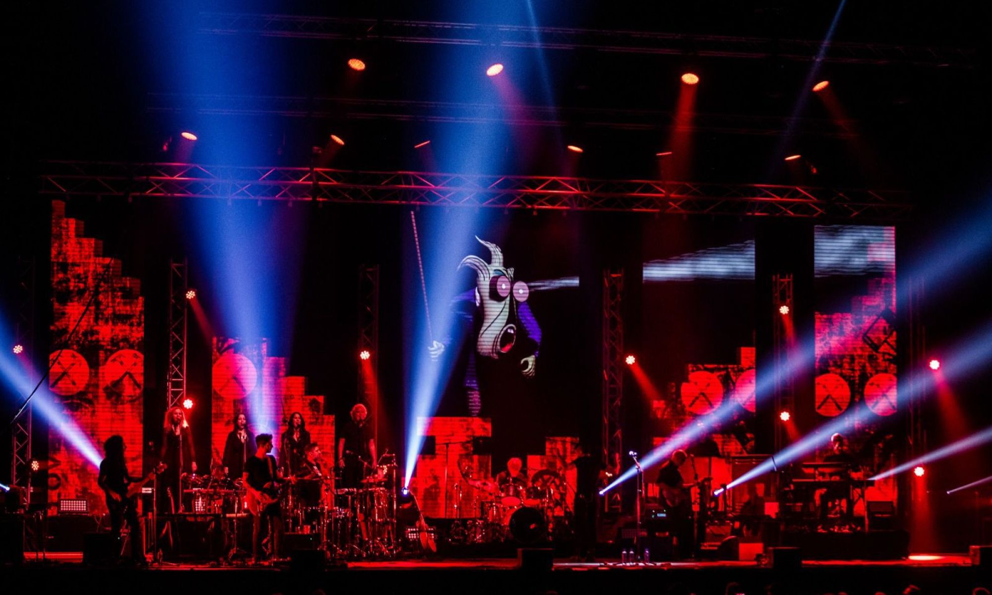 A stage with musicians shining spotlight out to the audience. A cartoon is projected on the wall.