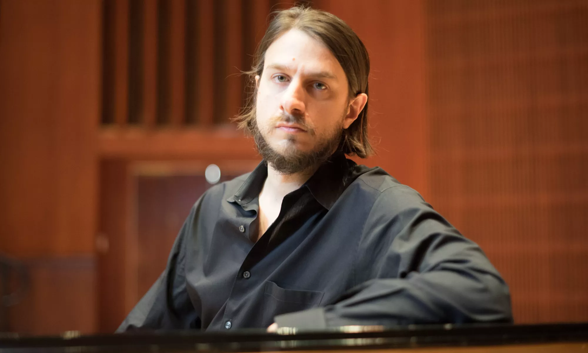 Thomas Schwan leans on a piano.