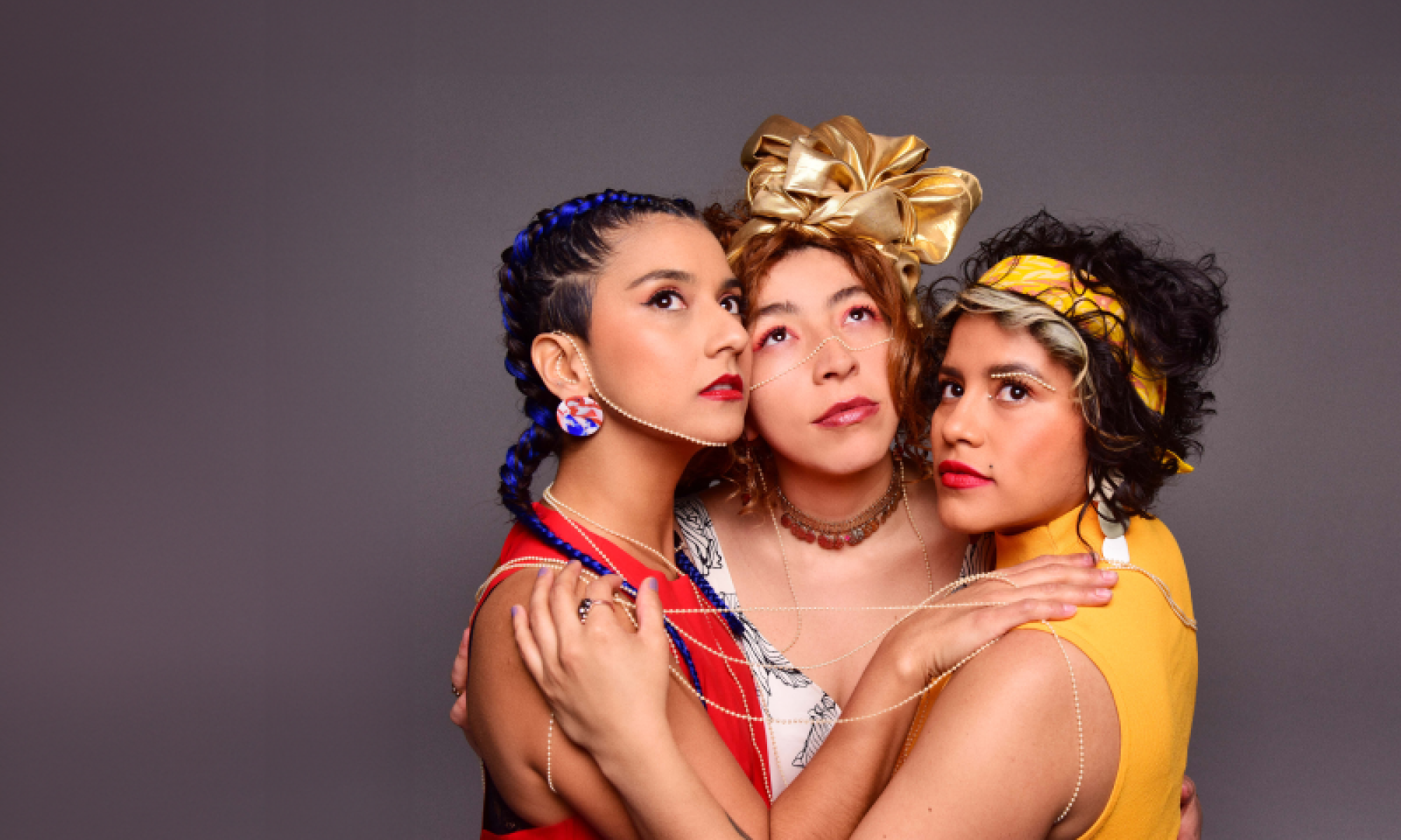 Three women huddle together and look up.