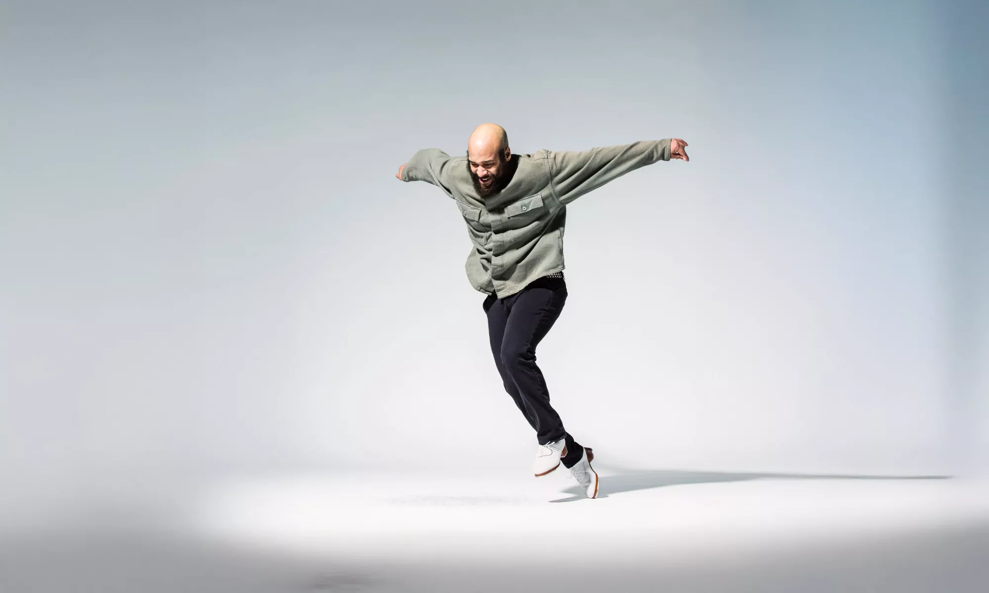 A tap dancer about to step. His arms are outstretched.