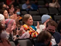 Several audience members clapping at a performance