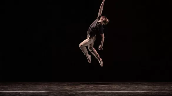 dancer leaps upward with one hand in the air