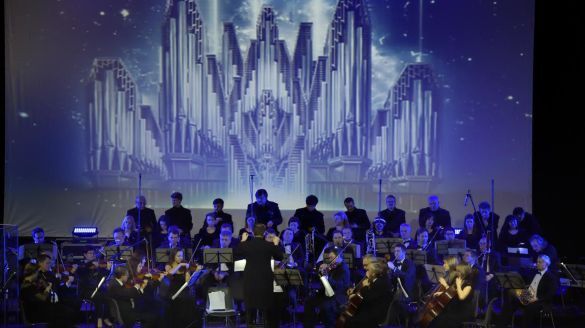 An orchestra on stage with projections happening behind them.