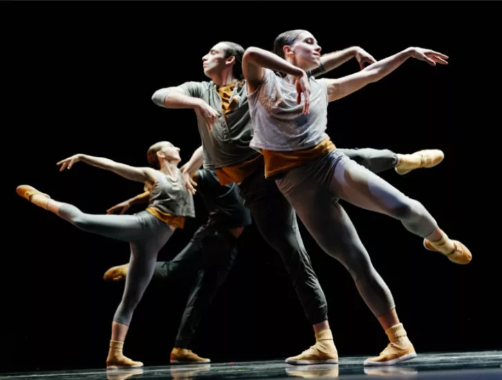 Dancers stand in a line holding a arabesque.